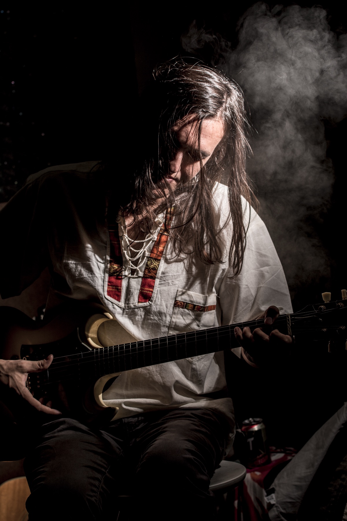Alex Koch playing guitar in a smoke-filled studio portrait